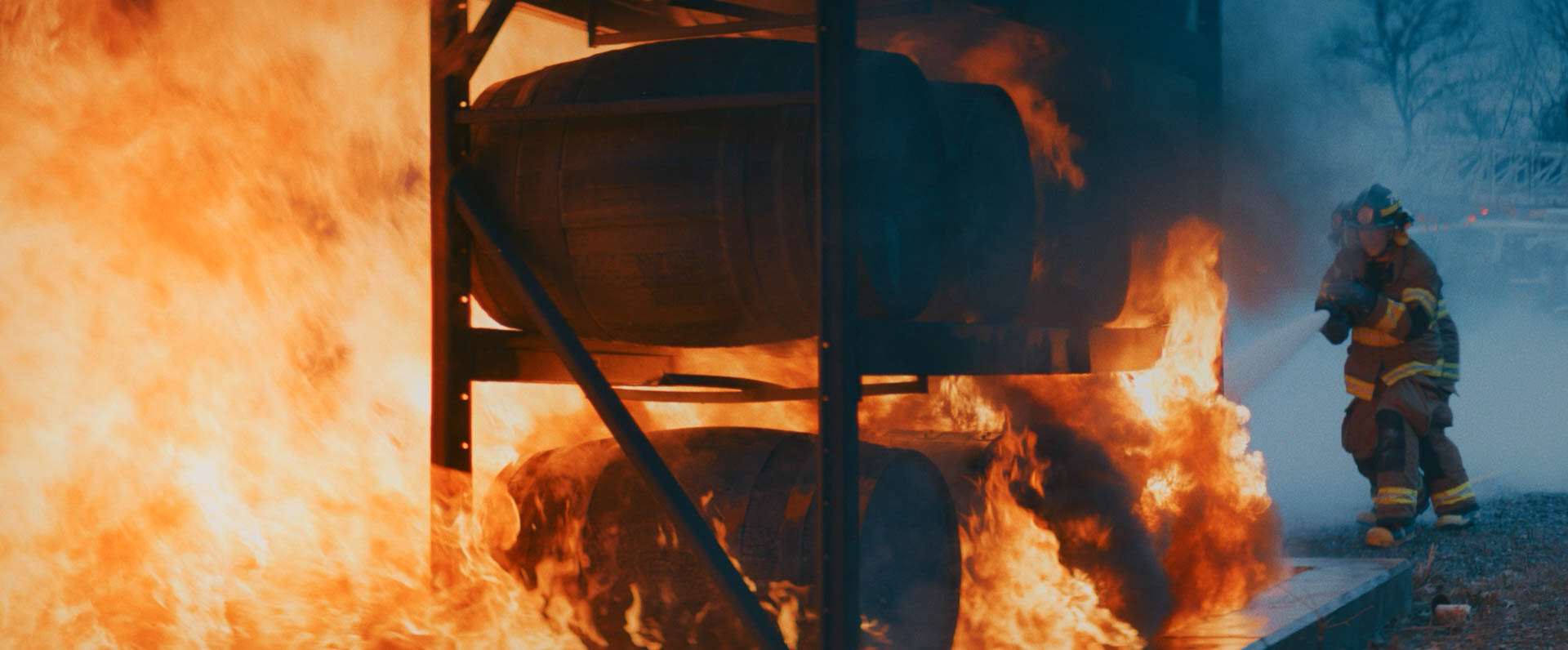 Barrels of Jack Daniel's whiskey on fire being put out by a fireman.