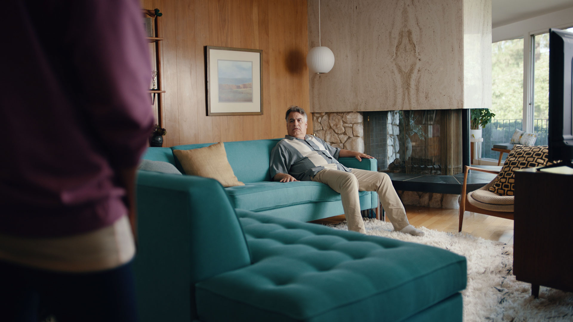 A man sitting on a couch looking at another person.