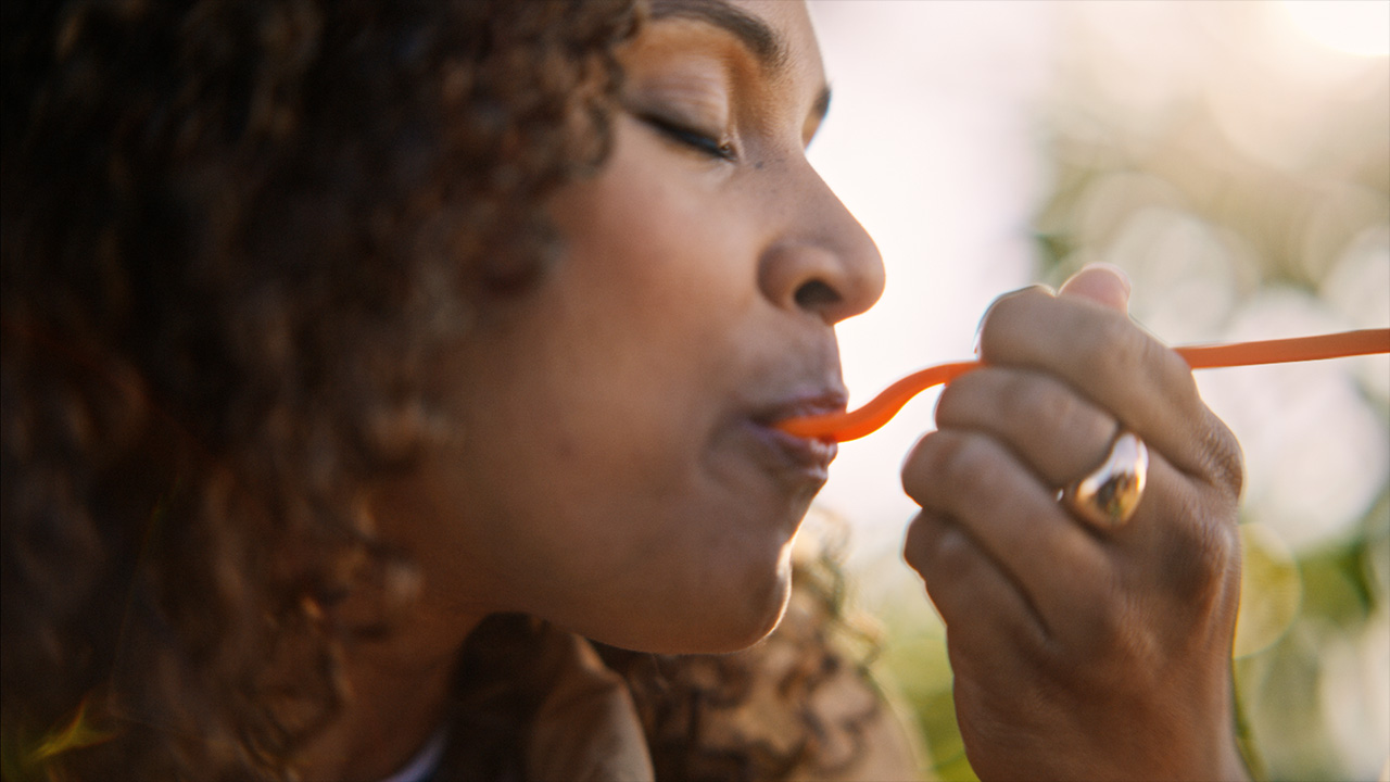 A woman takes a bite from a Salad and Go brand salad with an orange fork